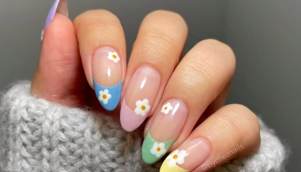 multi-colored pastel french tip nails with small white daisy floral accents on a hand