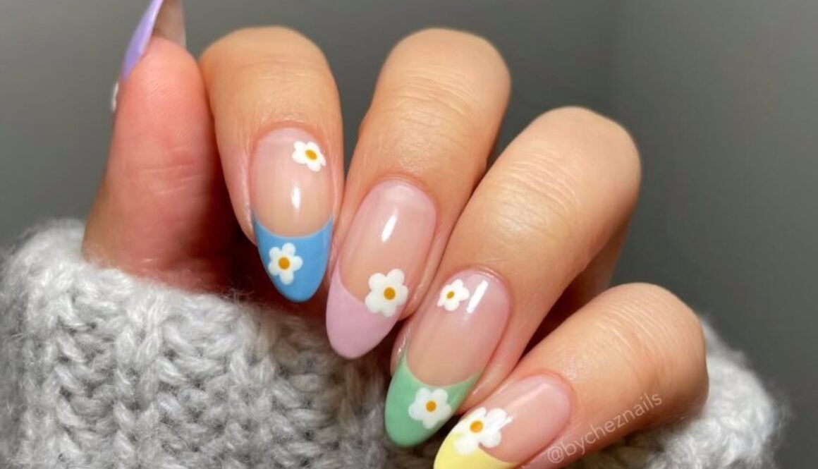 multi-colored pastel french tip nails with small white daisy floral accents on a hand