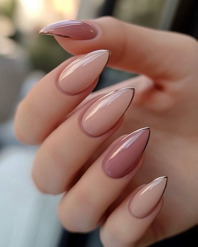 almond shaped nails with nude and mauve ombre polish and thin gold metallic outlines.