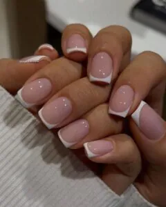 glossy nude square nails with classic white french tips and a white sweater.