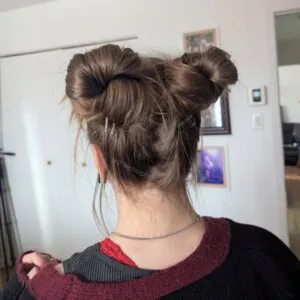 rear view of a woman with light brown hair styled in two messy space buns.