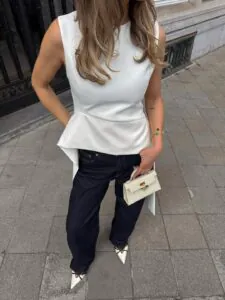 woman wearing white sleeveless peplum top with dark wash denim jeans