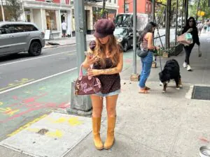 woman in brown polka dot top and denim shorts carrying a pink juicy couture handbag