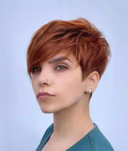 woman with a vibrant copper red pixie cut and side swept bangs