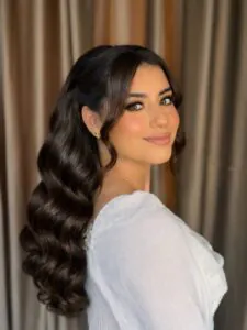 brunette woman with long glamorous waves and a soft side part bridal look