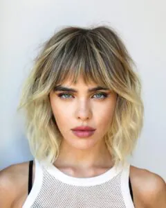 woman with a textured blonde lob haircut and wispy bangs