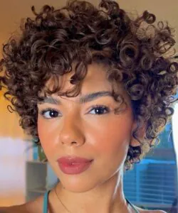 woman with a tight brown curly afro hairstyle and neutral makeup