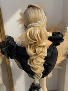 elegant blonde low ponytail with voluminous curls and a sparkling silver headpiece