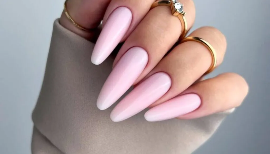 close-up photo of a hand featuring long, almond-shaped gel nails in a soft, creamy bubblegum pink.