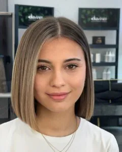 woman with a sleek blonde chin length bob haircut and middle part