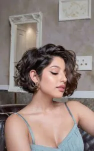 woman with a voluminous dark brown wavy bob haircut and gold earrings
