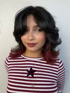 woman with layered black hair featuring red dyed ends and curtain bangs