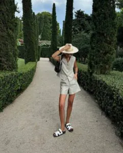 woman in sage green vest and shorts set standing on garden path