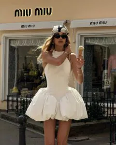 woman in a white bubble hem mini dress holding an ice cream cone outdoors.