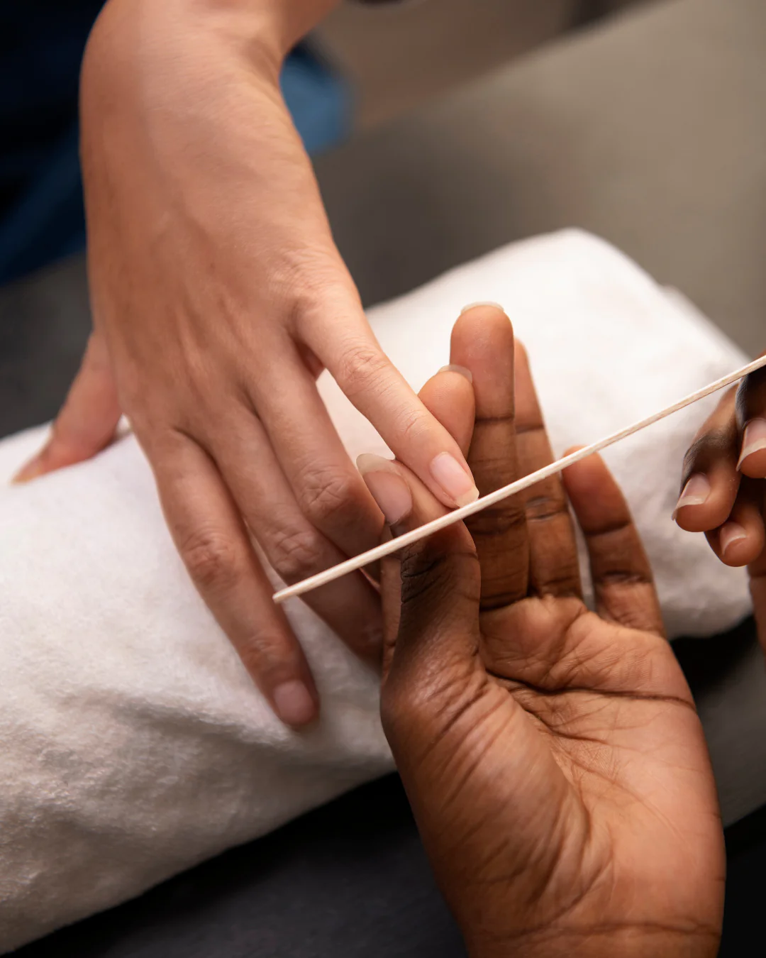 professional manicurist filing a clients fingernails over a white towel at a spa
