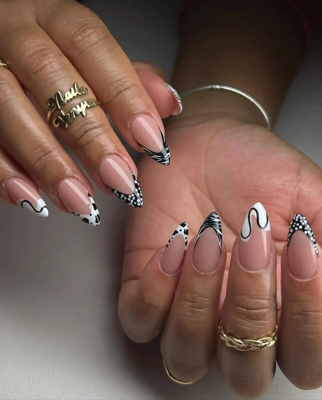 almond nails with eclectic black and white patterns including polka dots, stripes, and swirls.