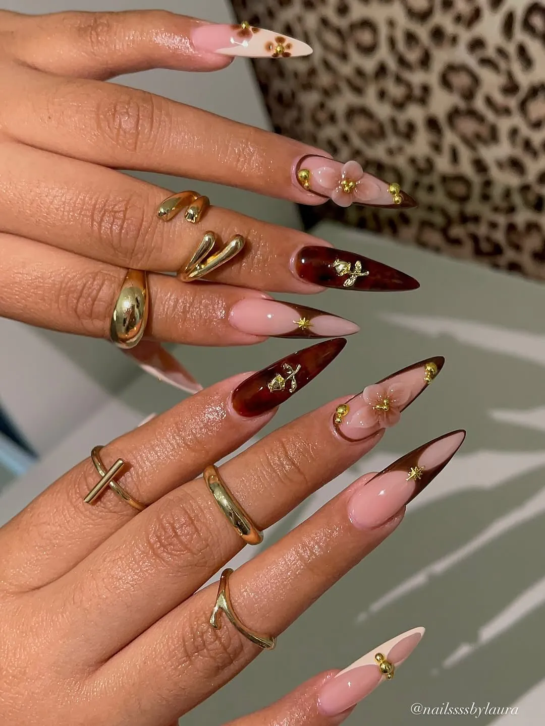 extra long almond nails with brown tortoise shell patterns, floral accents, and gold jewelry.
