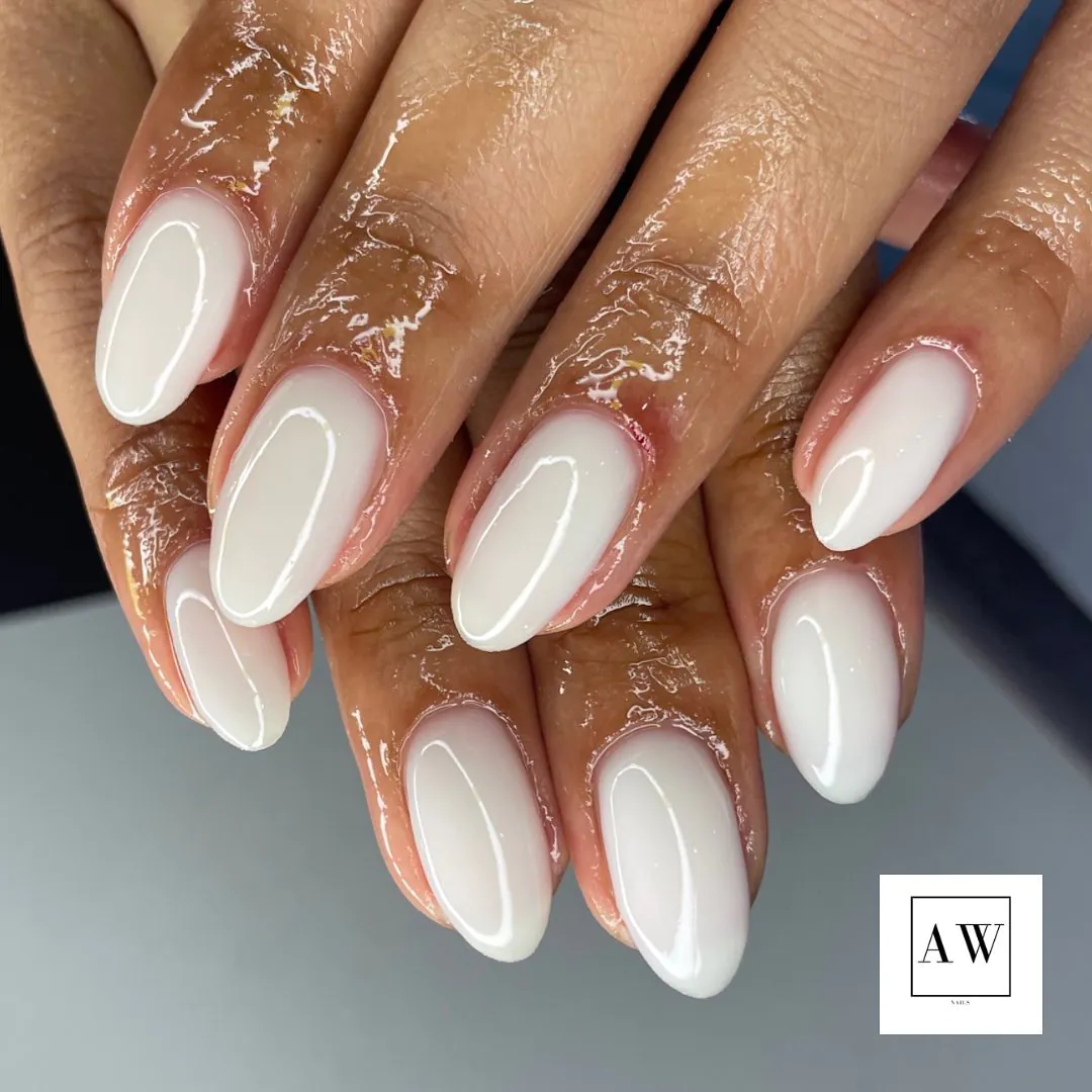 milky white almond nails with a high gloss finish on a person with deep skin.