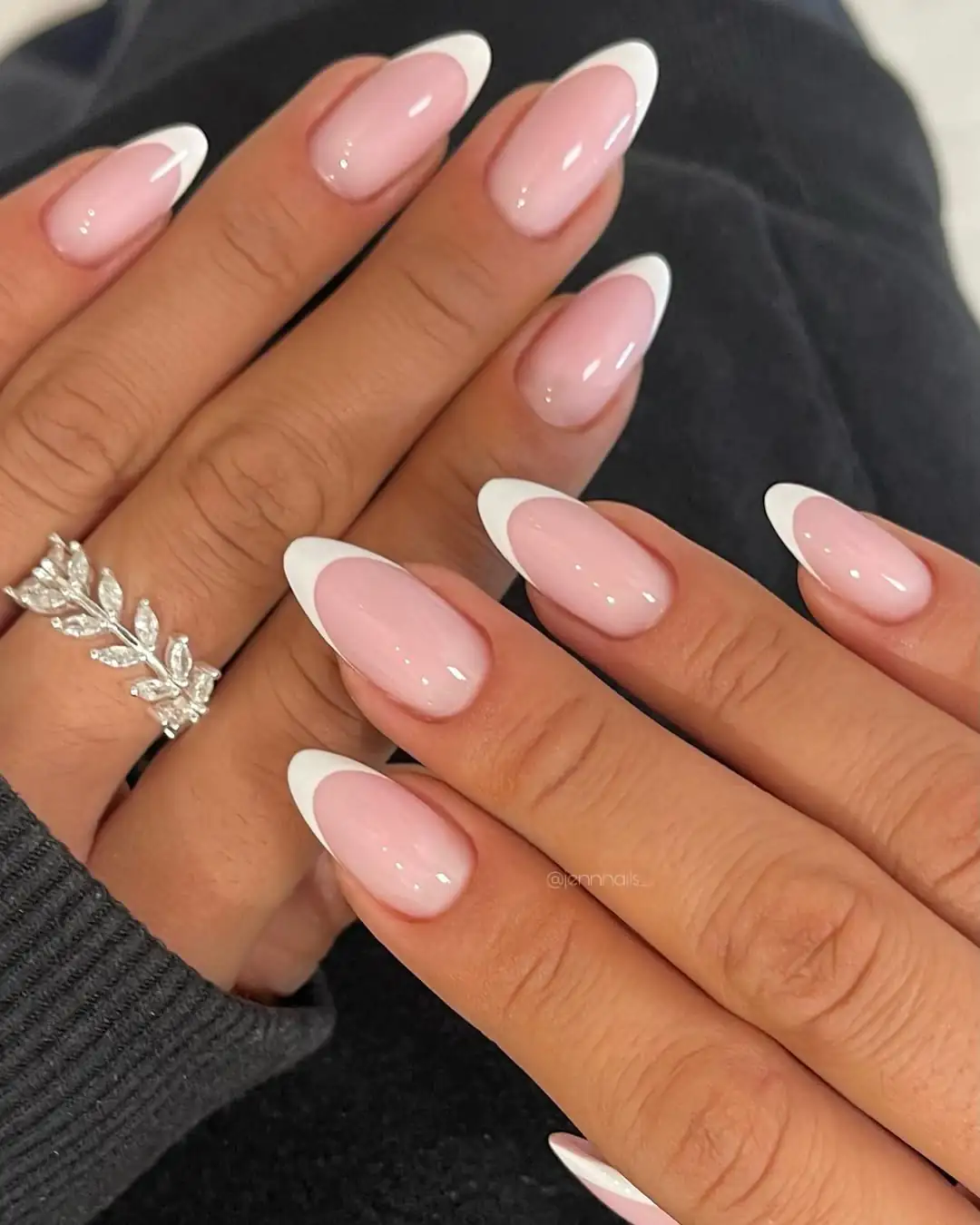 classic white french tip almond nails on a hand wearing a silver leaf ring.