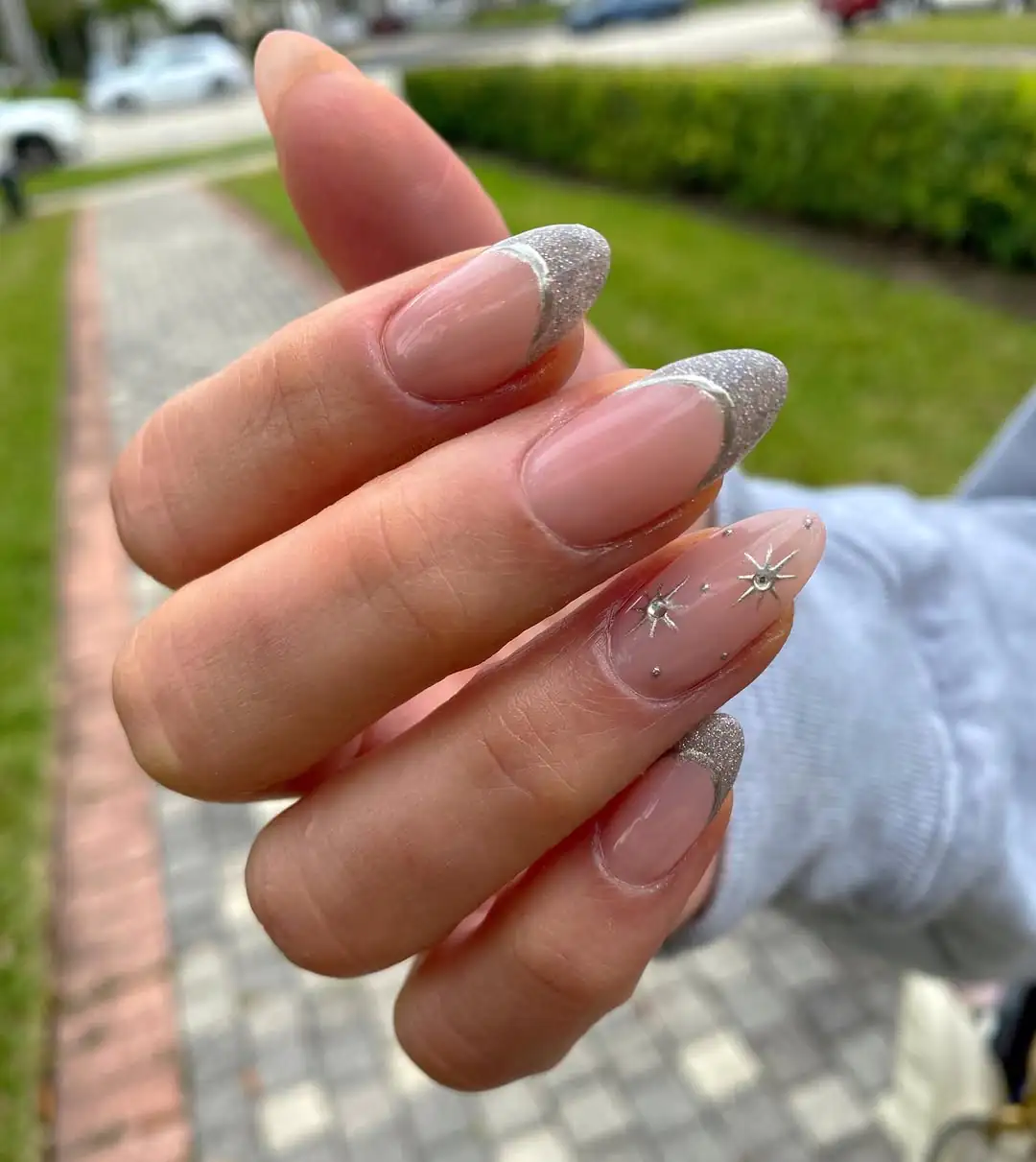 almond shaped nails with silver glitter french tips and chrome star accents
