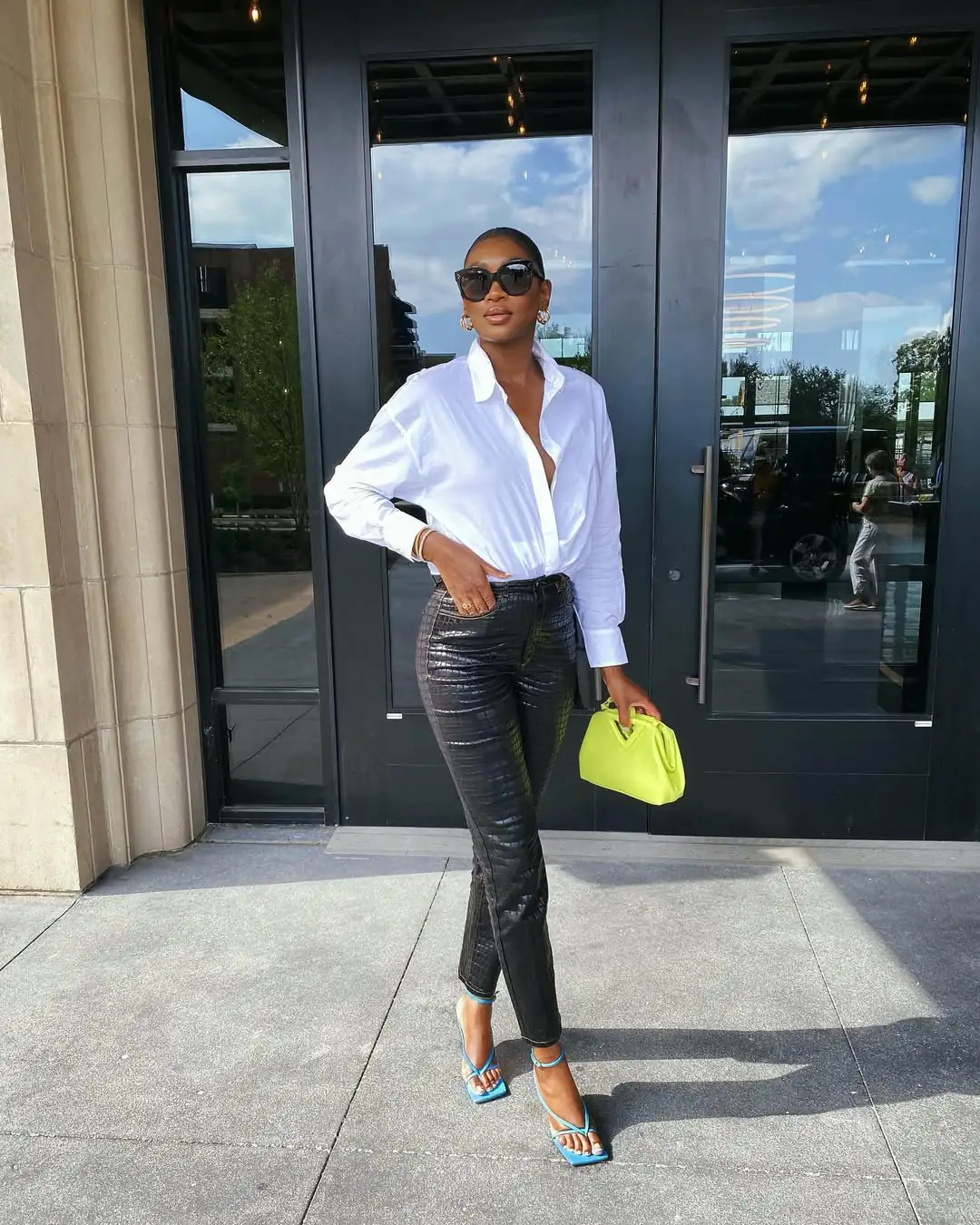 woman in white shirt and black crocodile-print leather trousers with lime green bag