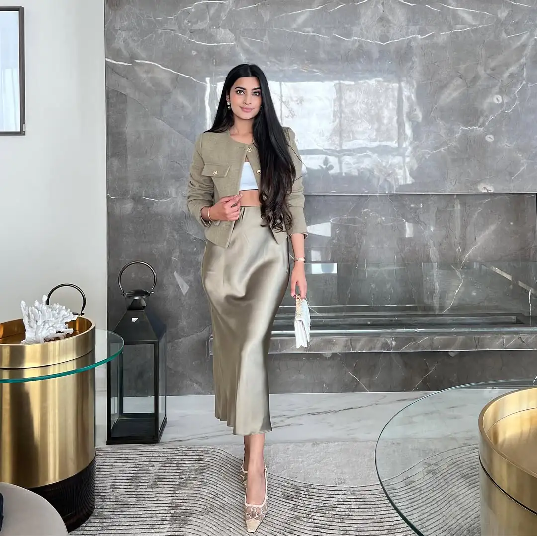 woman in olive cropped jacket and champagne satin midi skirt in modern room
