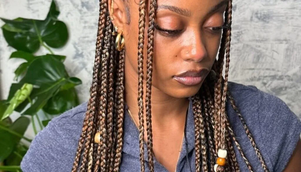 woman with half-up brown fulani braids featuring colorful wood beads and a top knot