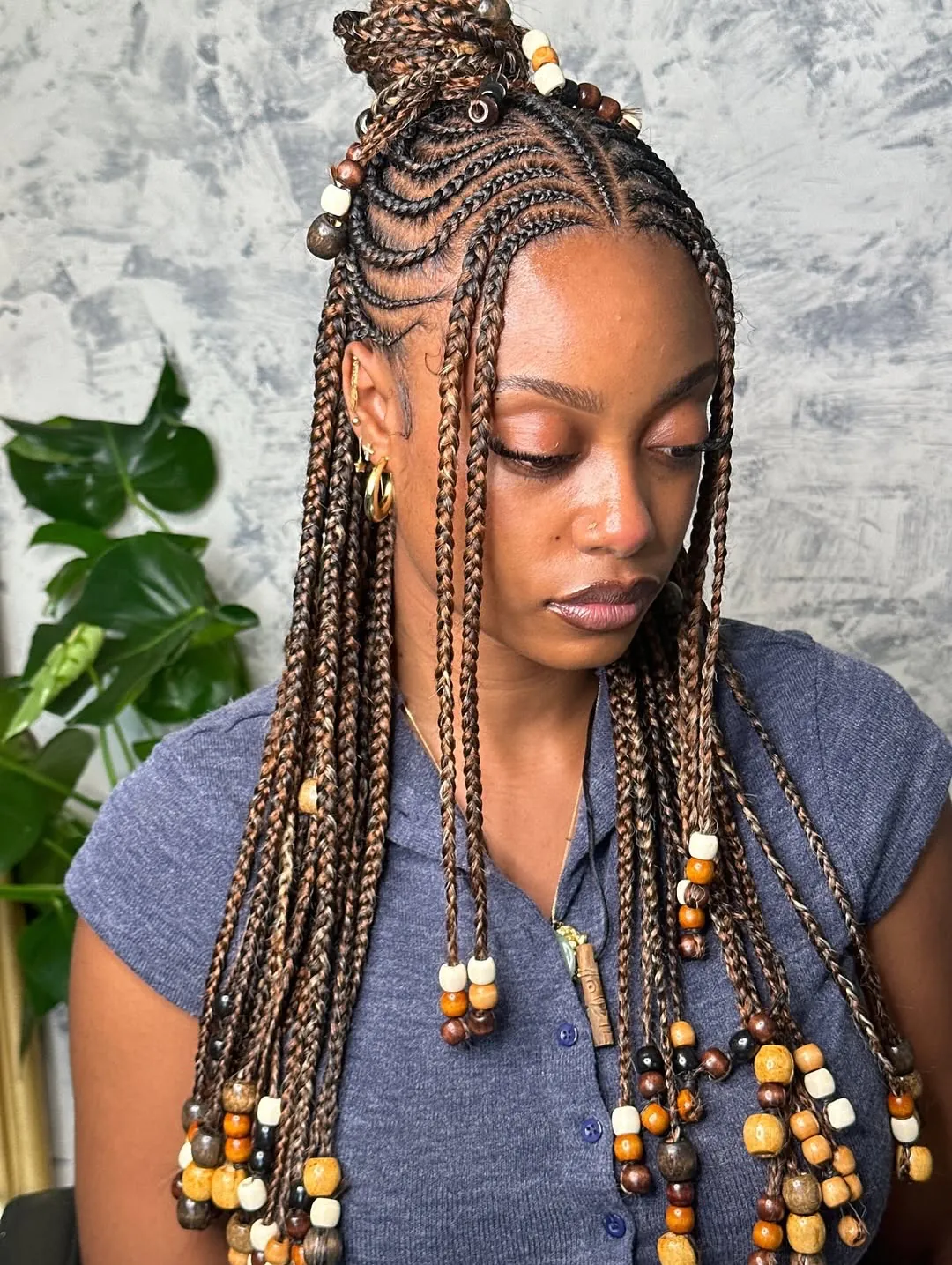 woman with half-up brown fulani braids featuring colorful wood beads and a top knot