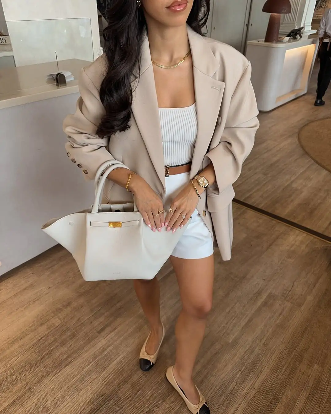 woman in beige oversized blazer and white shorts holding a cream leather tote bag