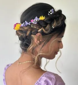 brunette woman with braided crown hairstyle featuring small colorful spring flowers