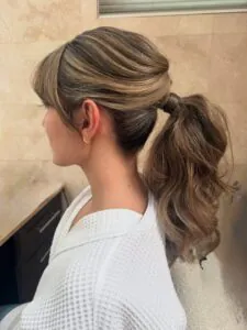 woman with textured blonde highlighted ponytail and face framing curtain bangs