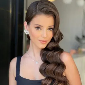 brunette woman with side swept hollywood waves hairstyle and flower earring