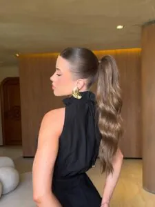 woman with long wavy brunette ponytail and elegant gold statement earring