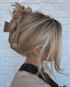 woman with blonde hair in a messy bun secured by a brown matte claw clip