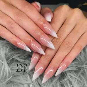 sharp stiletto nails with a soft pink to white ombre fade and glossy finish