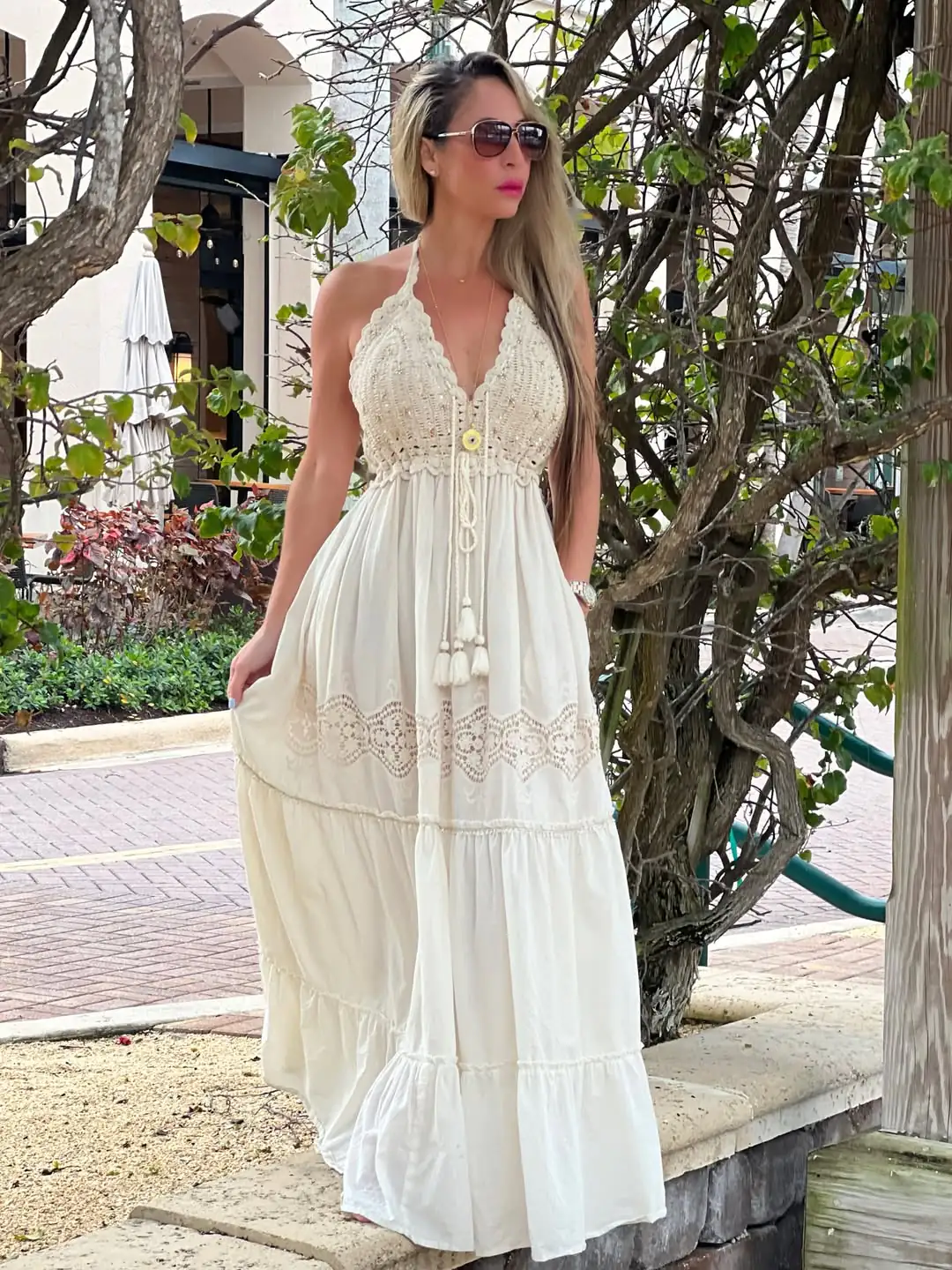 woman in white crochet halter maxi dress standing in a sunny outdoor setting