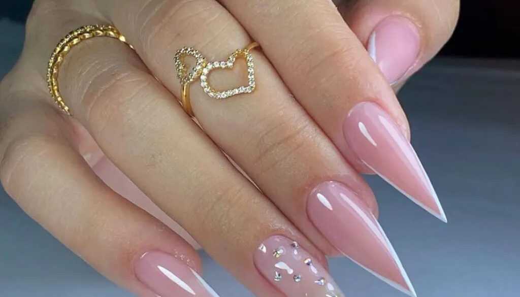 sharp nude stiletto nails with white v-shaped french tips and crystal accents
