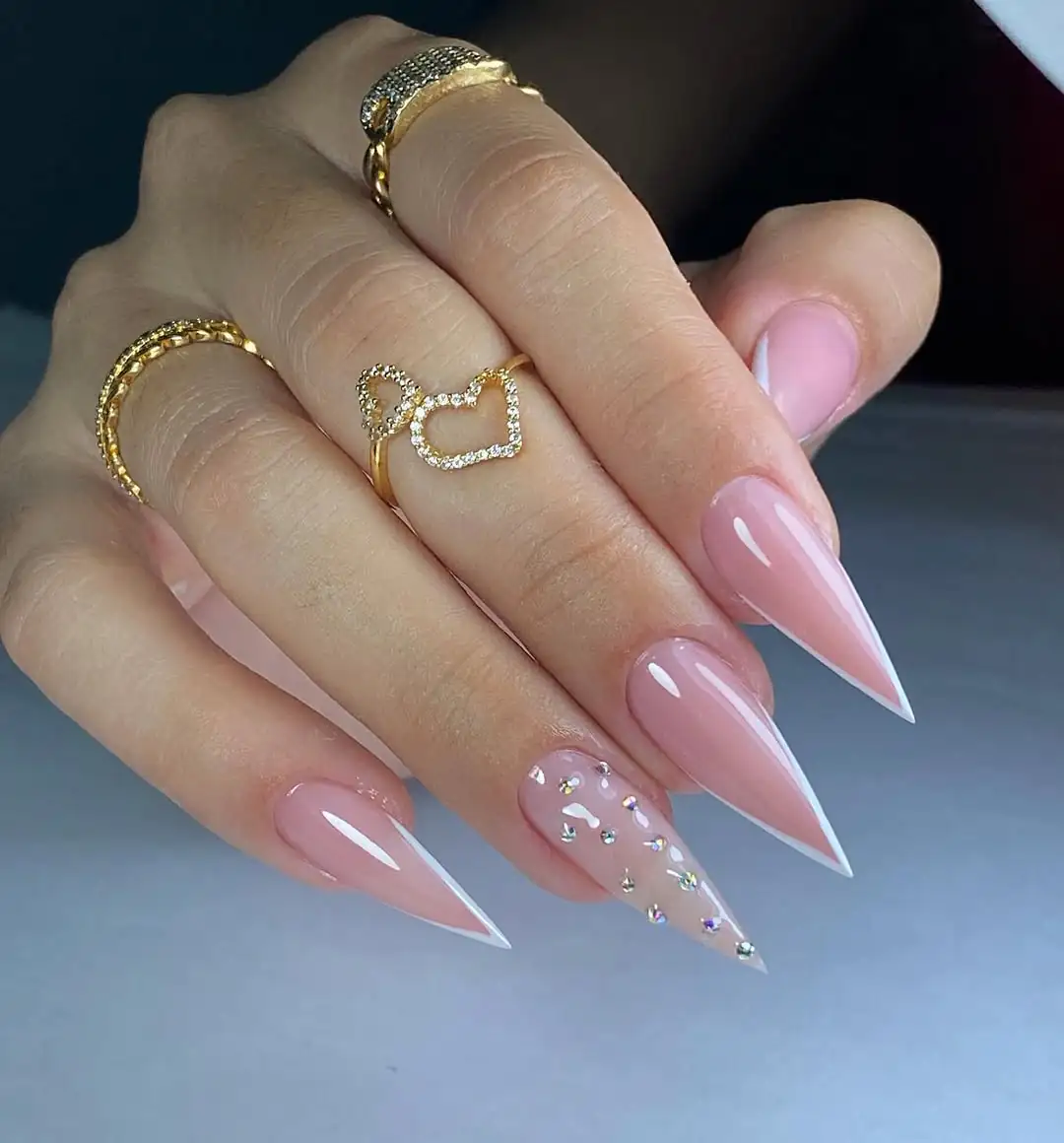 sharp nude stiletto nails with white v-shaped french tips and crystal accents