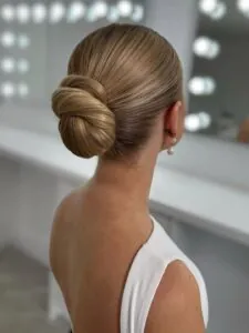 side view of woman with sleek blonde hair in low elegant bun and pearl earrings