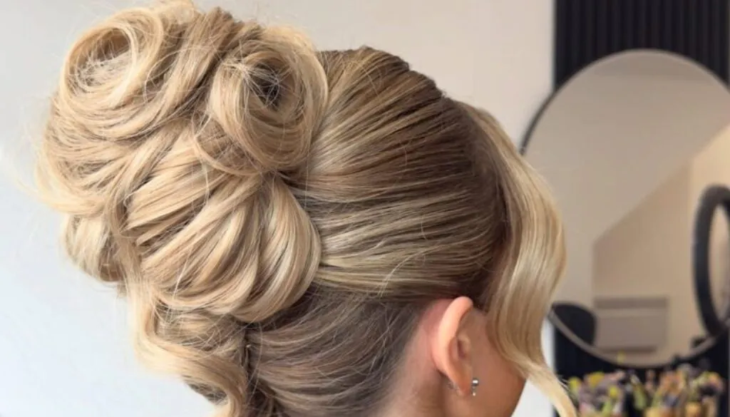 side view of woman with voluminous blonde wedding guest updo and face framing strands