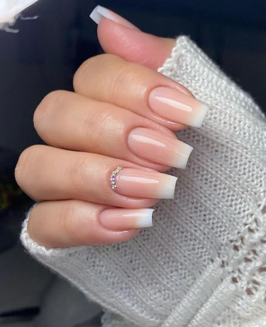 square ombré nails fading from nude to white with crystal accents