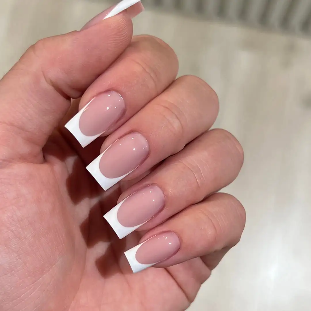 classic square white french tip nails on a hand with nude base
