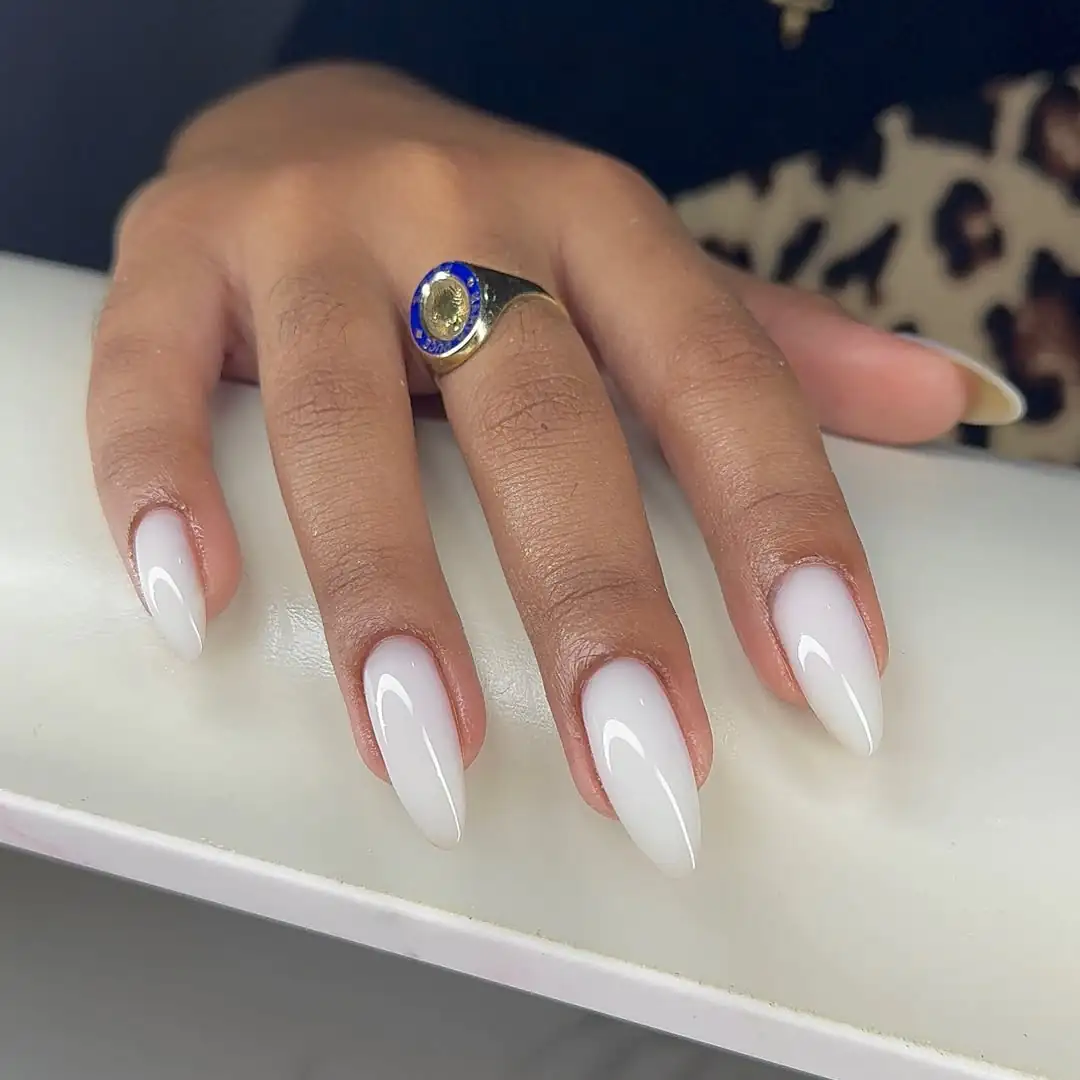long almond shaped milky white nails on a person wearing rings