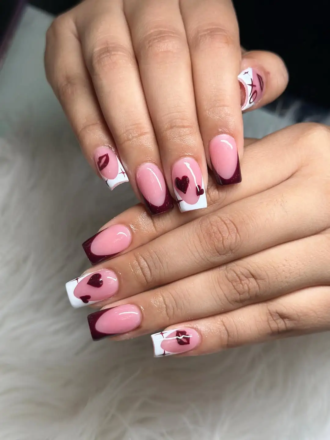 french manicure with deep burgundy tips and small dark heart accents