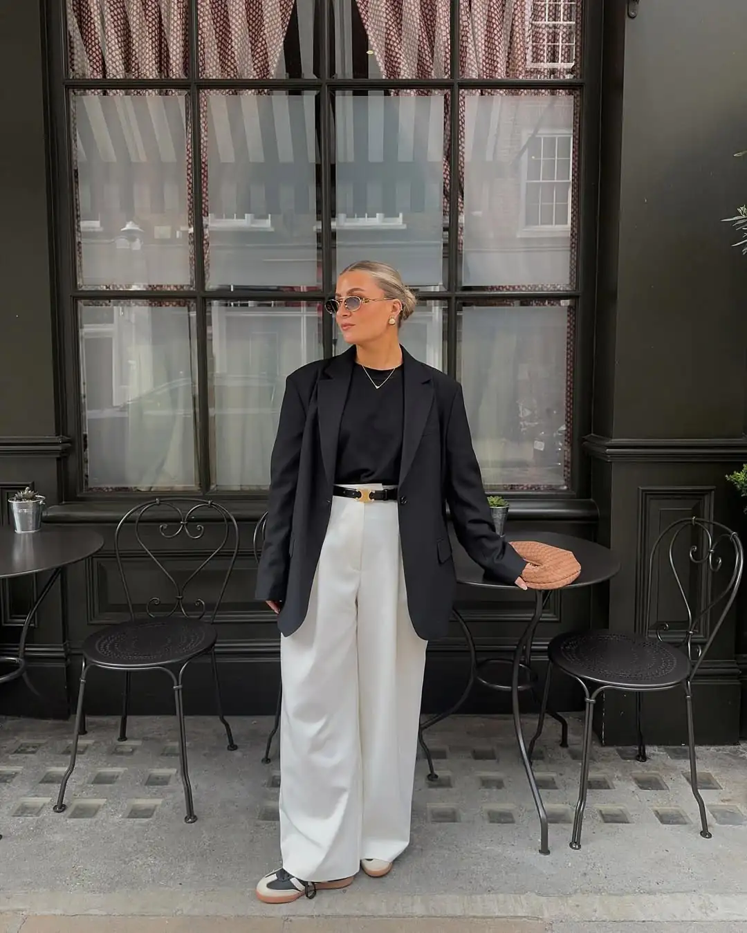 woman in black blazer and white wide-leg trousers at outdoor cafe