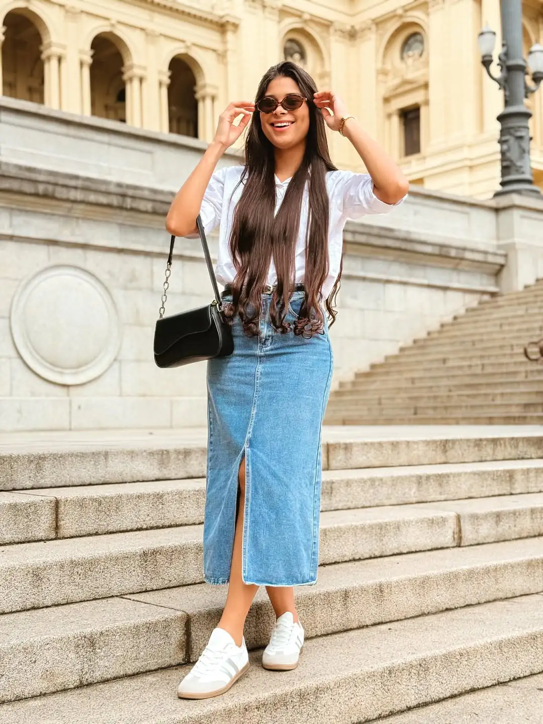 woman in white shirt and denim midi skirt standing on stone steps