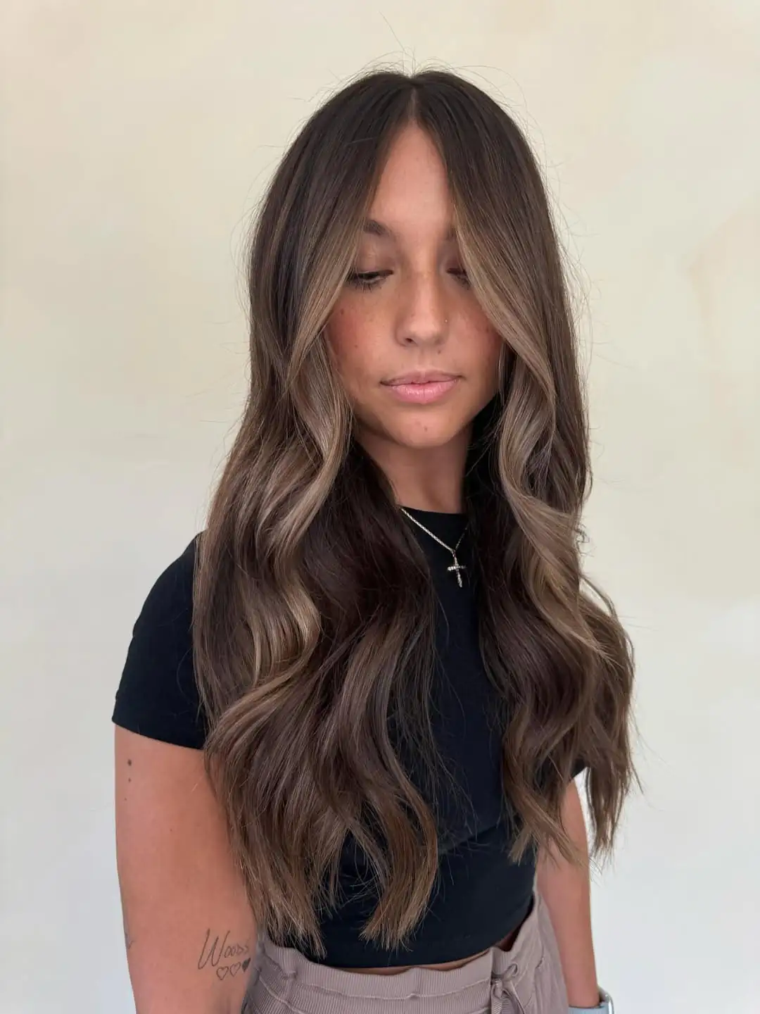 woman with long dark brown hair and light brown face framing highlights