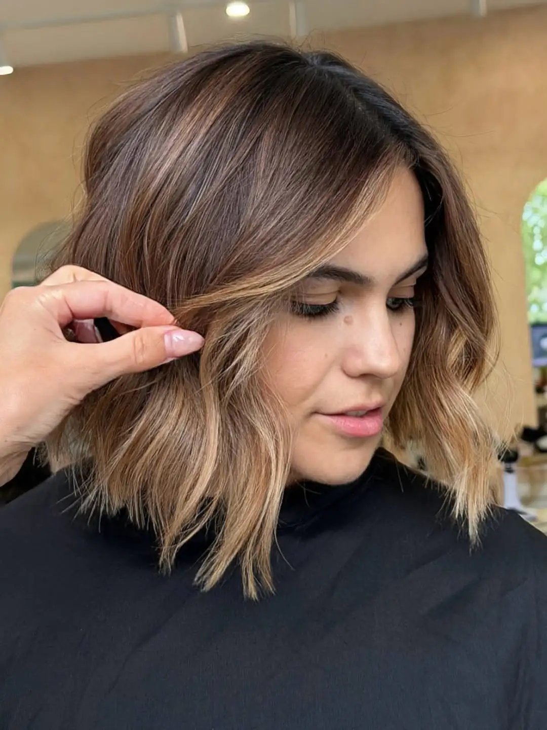 woman with a textured brunette bob featuring caramel highlights and soft beach waves