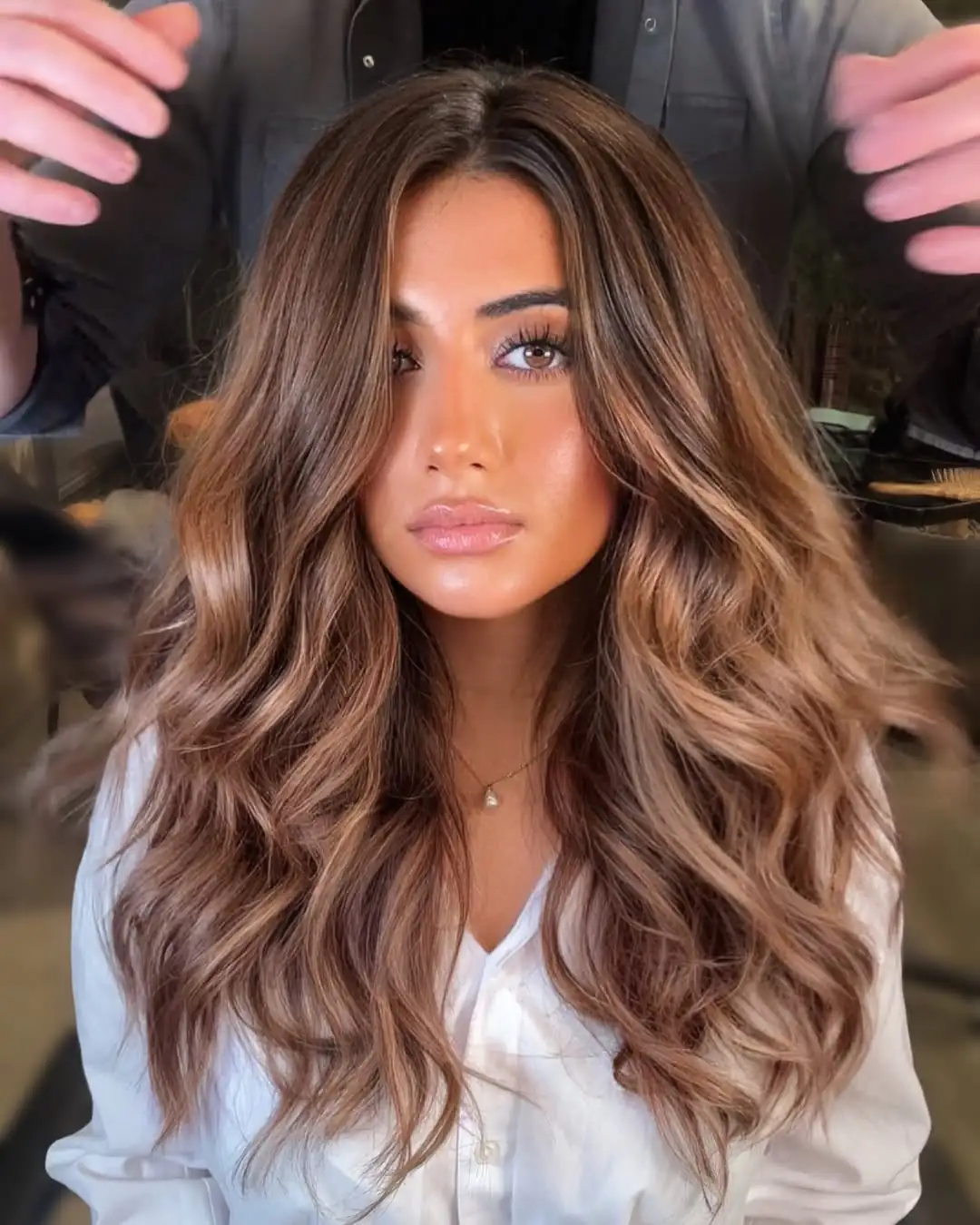 woman with warm brown wavy hair and subtle caramel highlights facing forward