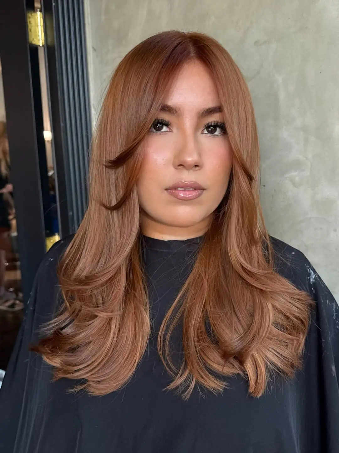 woman with copper red hair styled in voluminous waves and curtain bangs